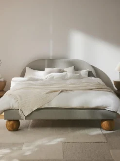 Cama tapizada con patas esfericas de madera Rena